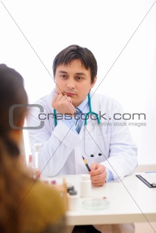 Medical doctor sitting at table and listens attentively patient