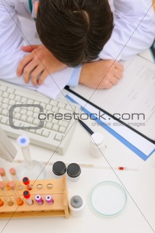Medical doctor sleeping on desk with medical stuff. Top view