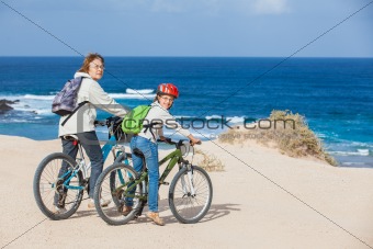 girl and her grandmother on bikes on the beach