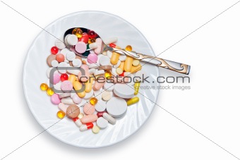Lot of colored pills on plate and spoon