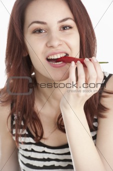 Young woman biting on a red chili pepper