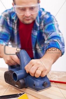 Man working wood with electric planer