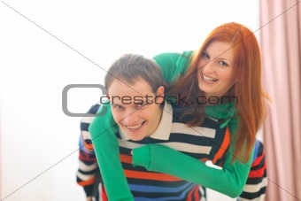 Smiling redhead girl piggybacking boyfriend