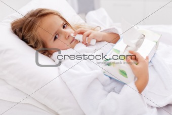 Little girl with bad cold - using nasal spray and paper napkins