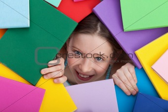Young girl emerging from beneath books