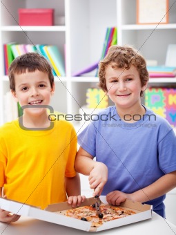 Happy boys cutting pizza