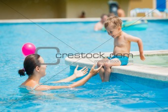 boy with mather playing in a pool of water