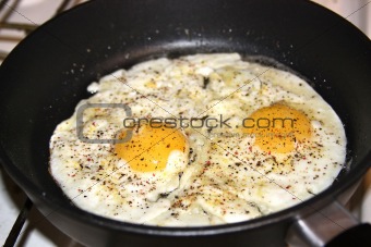 Spicy fried eggs in pan, sunny side up