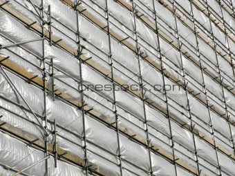 Close up of a high rise building covered in white tarpaulin.