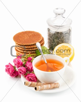 tea in cup with biscuits and bouquet roses