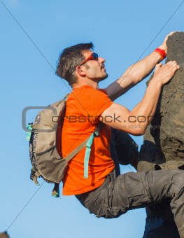 Young man in glasses with backpack climbing