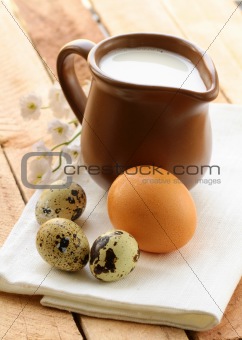 Ceramic jug with milk and eggs on a wooden table , rustic style
