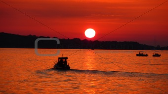 Fishermen on sea at red sunset