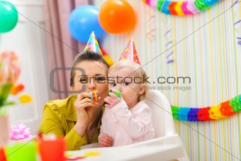 Baby and mother blowing into party horn