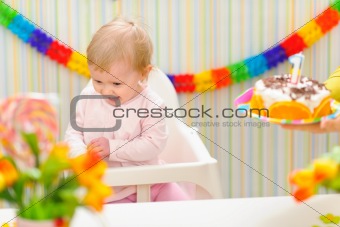 Baby happy and embarrassed receiving birthday cake