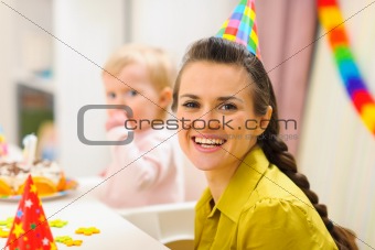 Portrait of mother and baby eating birthday cake in background