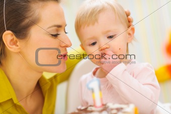 Mother congratulating eating first birthday cake baby