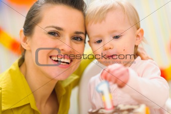 Portrait of mom and baby eating birthday cake