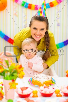 Smiling mother and eat smeared baby on birthday celebration party