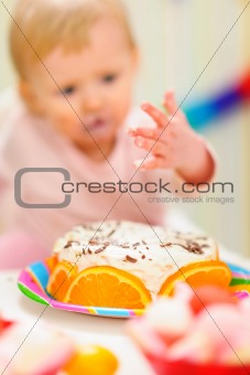 Closeup on birthday cake and eat smeared baby in background|anonymous