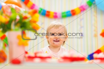 Portrait of eat smeared baby celebrating first birthday