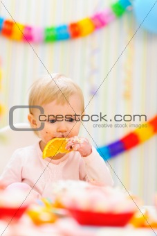 Baby eating orange on first birthday celebration party