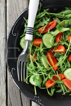 salad with arugula and cherry tomatoes on black vintage plate