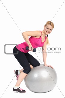 Young woman doing Standing Bent-Over Dumbbell Triceps Extension on Fitnes Ball, phase 1 of 2.