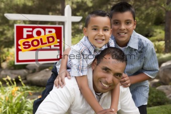 Hispanic Father and Sons in Front of a Sold Home For Sale Real Estate Sign.