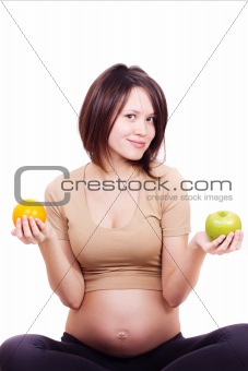 beautiful pregnant woman holding an orange and an apple in her hands