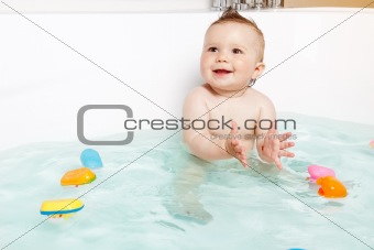 Cute baby clapping hands and smiling while taking a bath