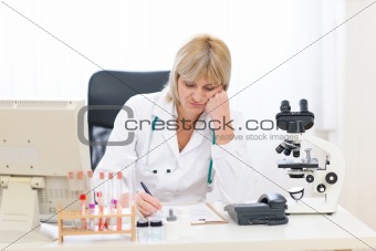 Bored senior doctor woman working at office