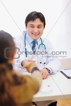 Happy medical doctor and patient shaking hands