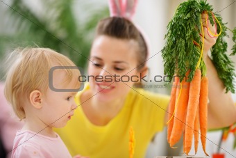 Mother showing baby bunch of carrots