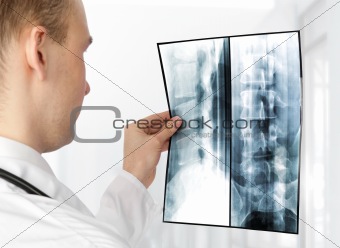 Rear view of young male doctor examining a xray