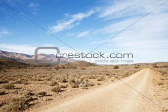 Dirt road in arid region leading away from viewer