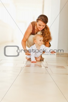 Happy mother helping baby to creep