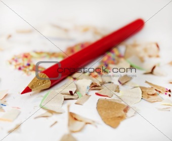 Sharp red pencil among pencils shavings on white background