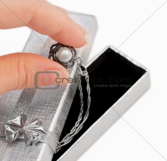 Closeup of hand holding a necklace with one pearl isolated on white