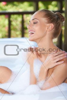 Laughing woman enjoying a bubble bath