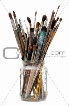 Assorted dirty old painting brushes in a glass flask