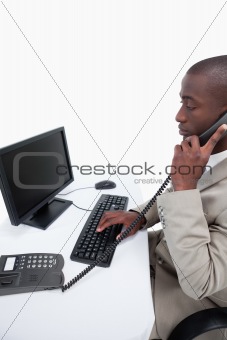 Side view of a secretary answering the phone while using a computer