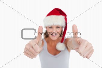 Smiling woman with the thumbs up and a Christmas hat