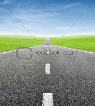 green field and road over blue sky
