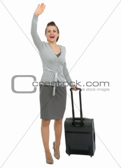 Excited traveling woman with suitcase waving hand