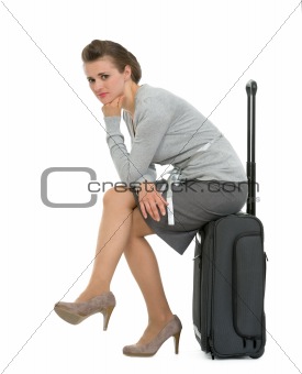 Upset traveling woman sitting on suitcase