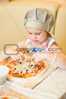 Little girl adding cheese in pizza