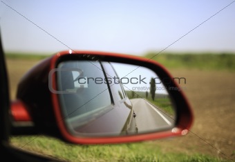 Road and trees reflected in rear-view mirror