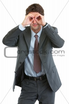 Modern businessman looking through binoculars shaped hands