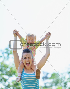 Happy mother with baby sitting on shoulders